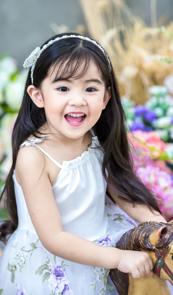 Улыбающаяся маленькая девочка азиатка на лошадке