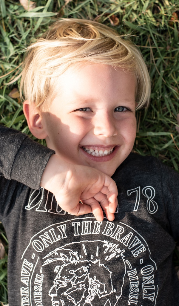 Улыбающийся маленький мальчик лежит на траве