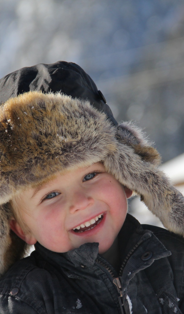 Улыбающийся  маленький мальчик в зимней шапке 
