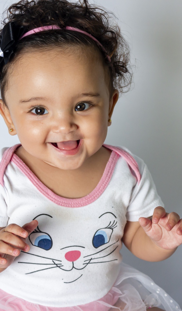 Улыбающаяся маленькая девочка на сером фоне 