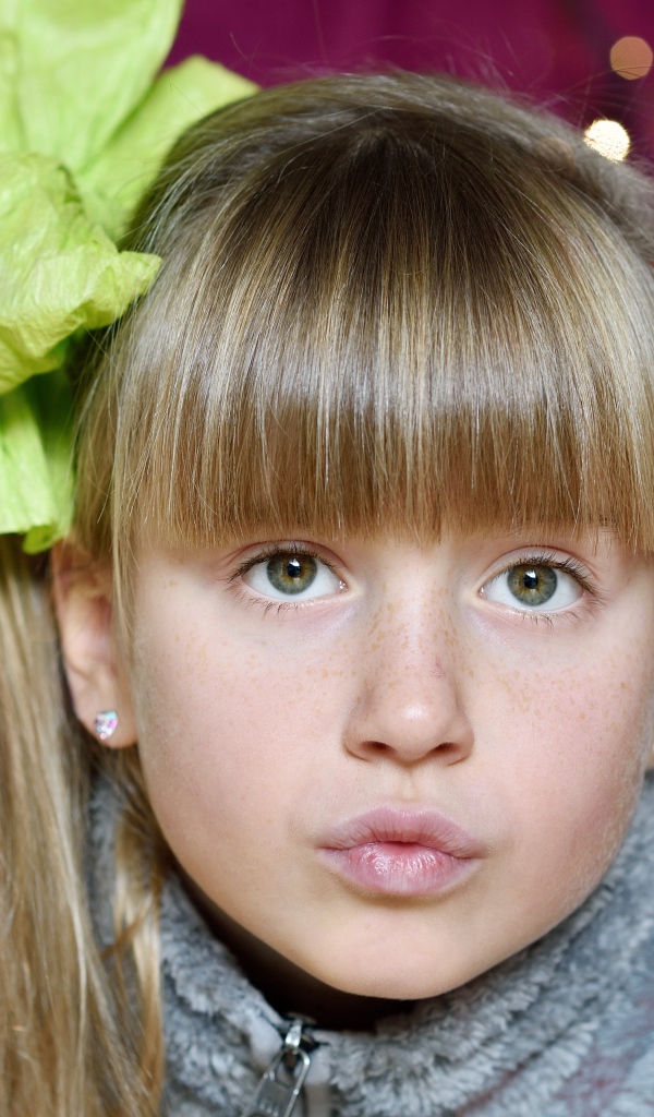 Лицо зеленоглазой девушки с бантом на голове 