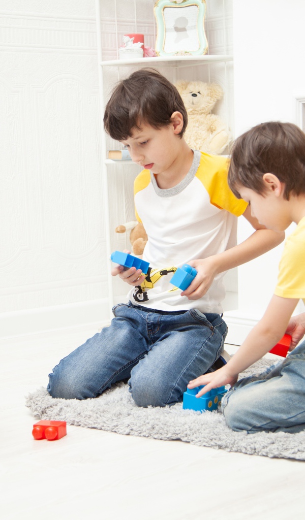 Два маленьких мальчика играет на полу