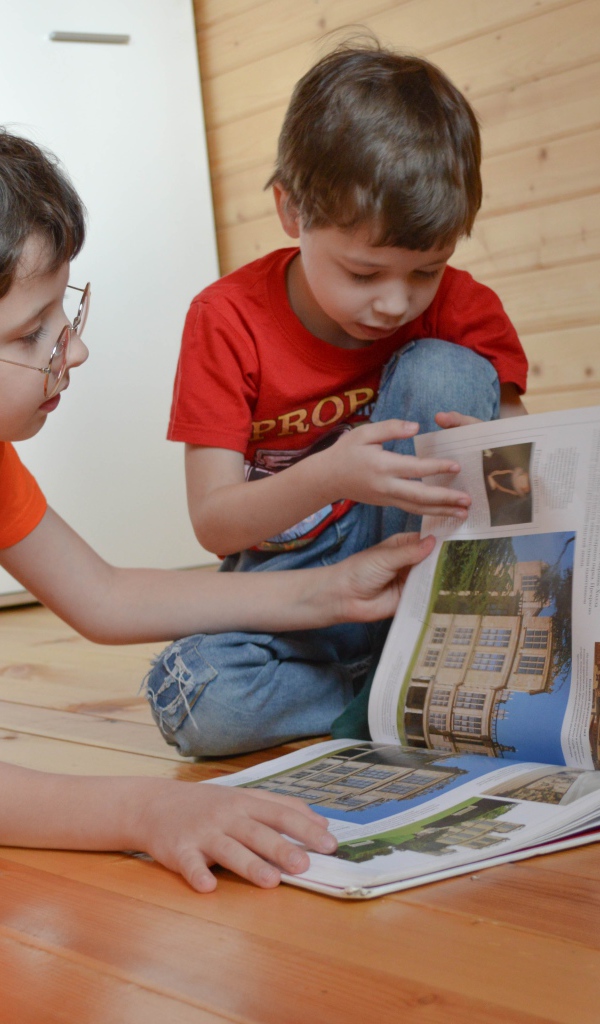 Два маленьких мальчика с книгой  на полу