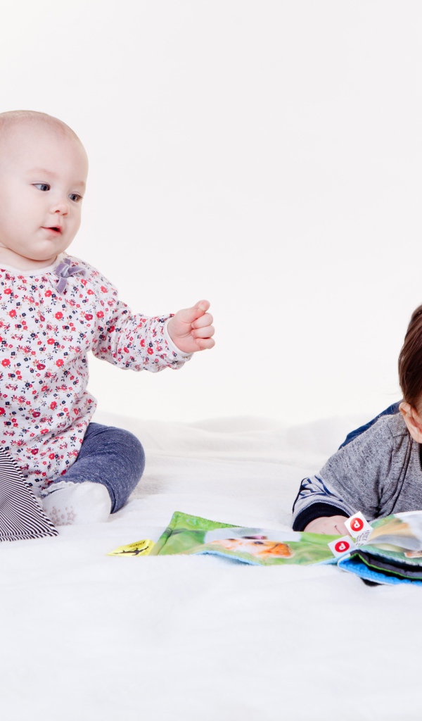 Два маленьких ребенка играют на белом фоне