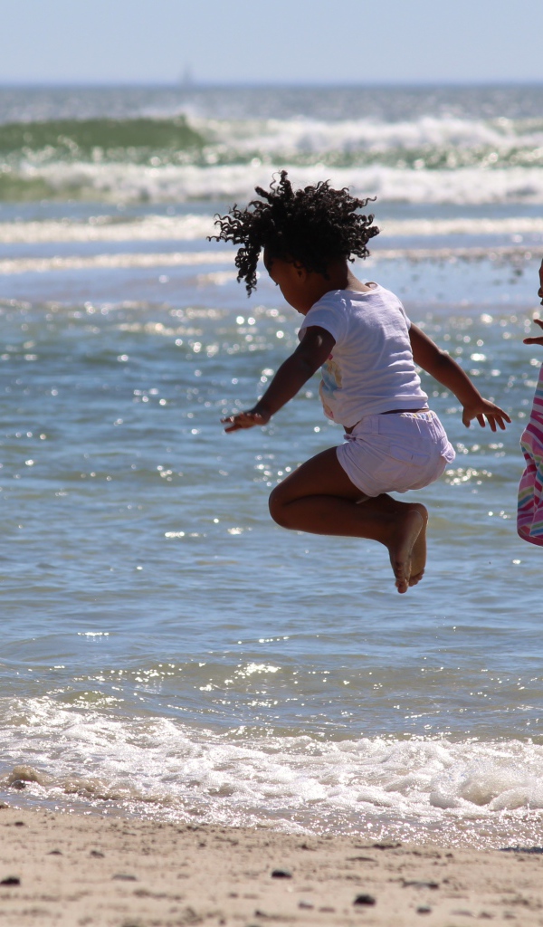 Две маленькие девочки играют на морском берегу