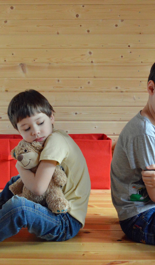 Два маленьких обиженных мальчика сидит на земле