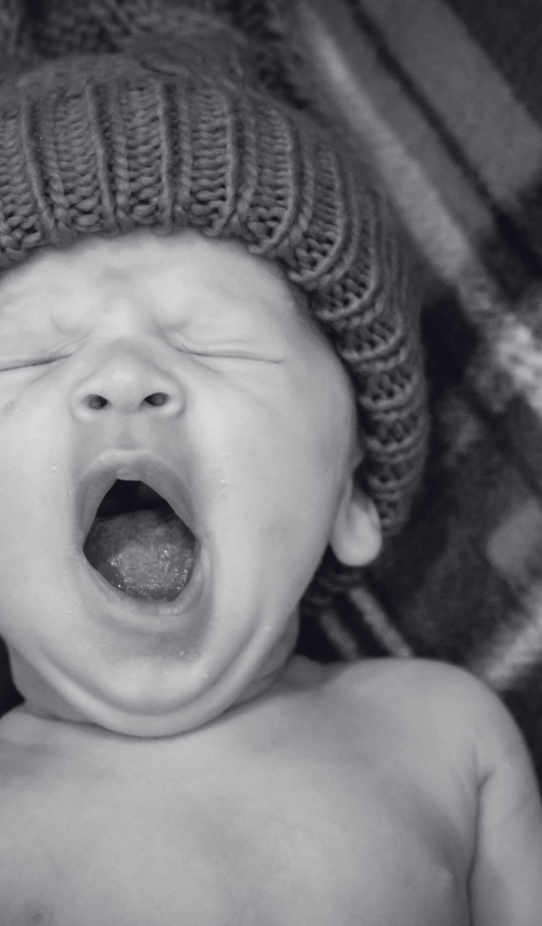 Зевающий ребенок в теплой шапке 