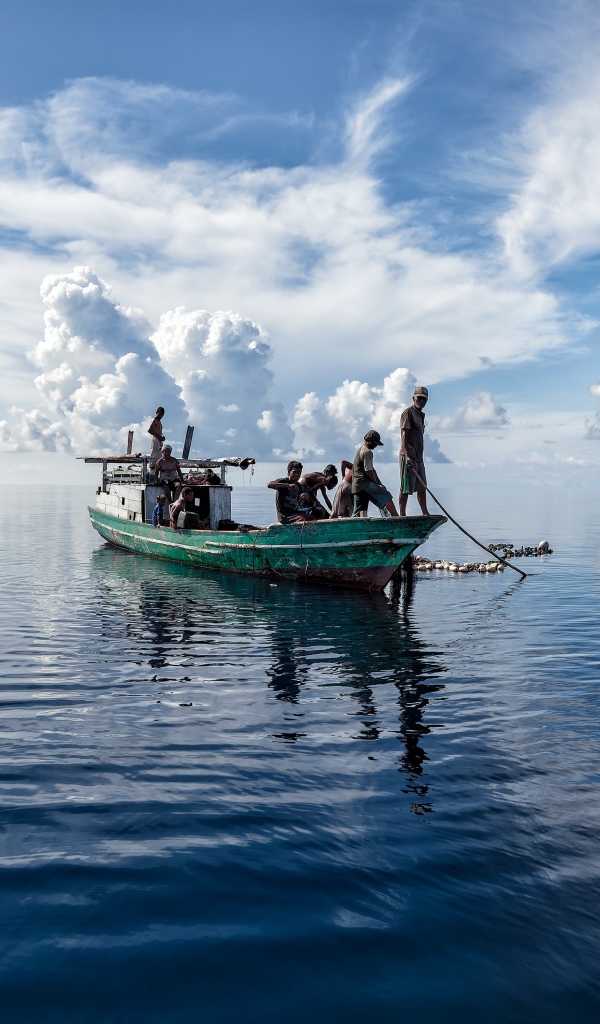 Лодка с рыбаками в море с белыми облаками 