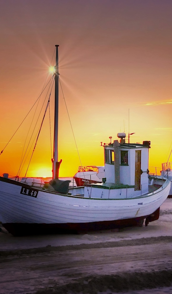 Рыбацкая лодка на берегу на закате 
