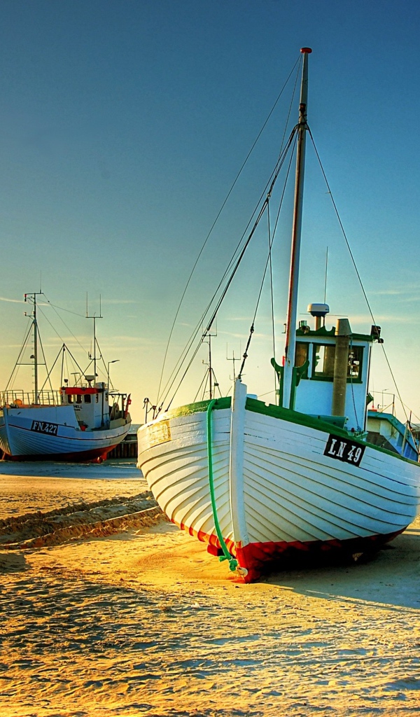 Рыболовные лодки в лучах солнца на берегу 