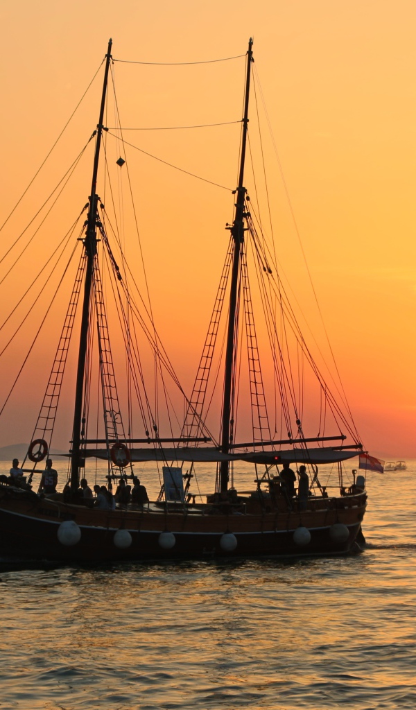 Large ship with lowered sails at sunset