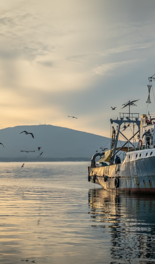 Старое рыболовное судно в море на закате 