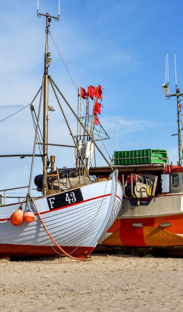 Две рыбацкие лодки стоят на песке у моря 