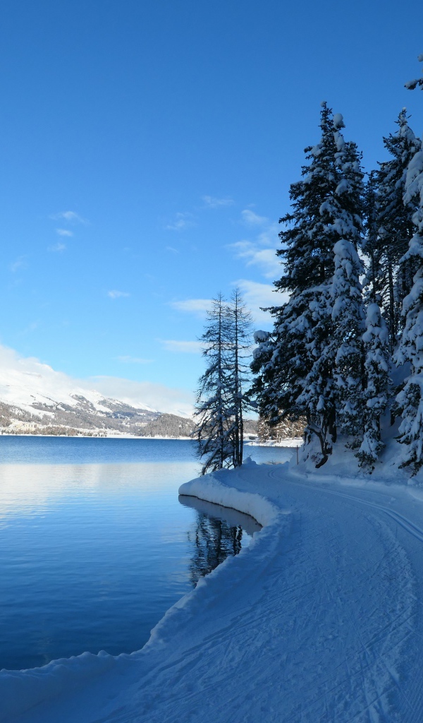 Покрытая снегом дорога у озера