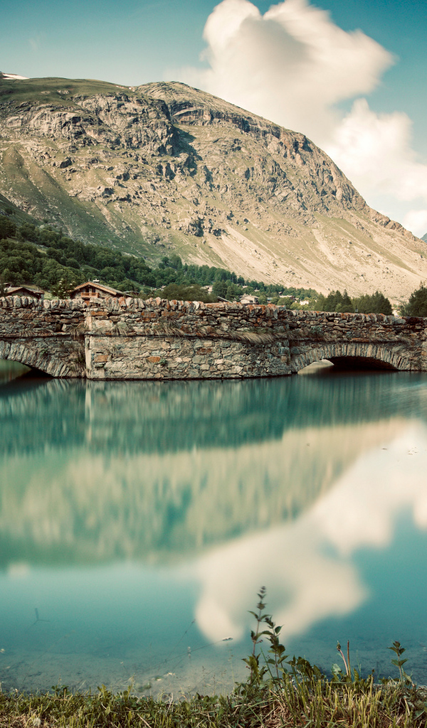 Old brick bridge on a lake near the mountain, France