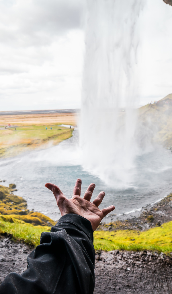 Рука тянется к водопаду Сельяландсфосс, Исландия