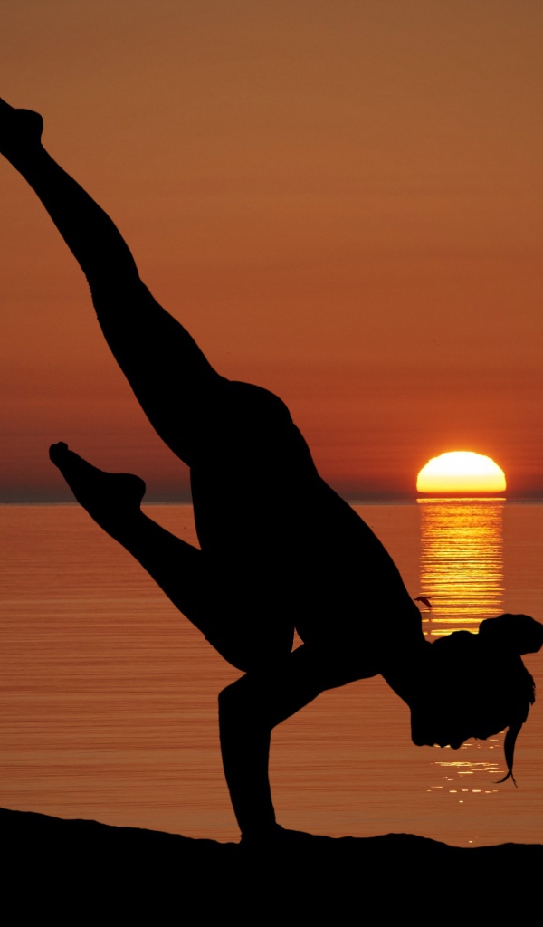 Девушка занимается йогой на закате солнца