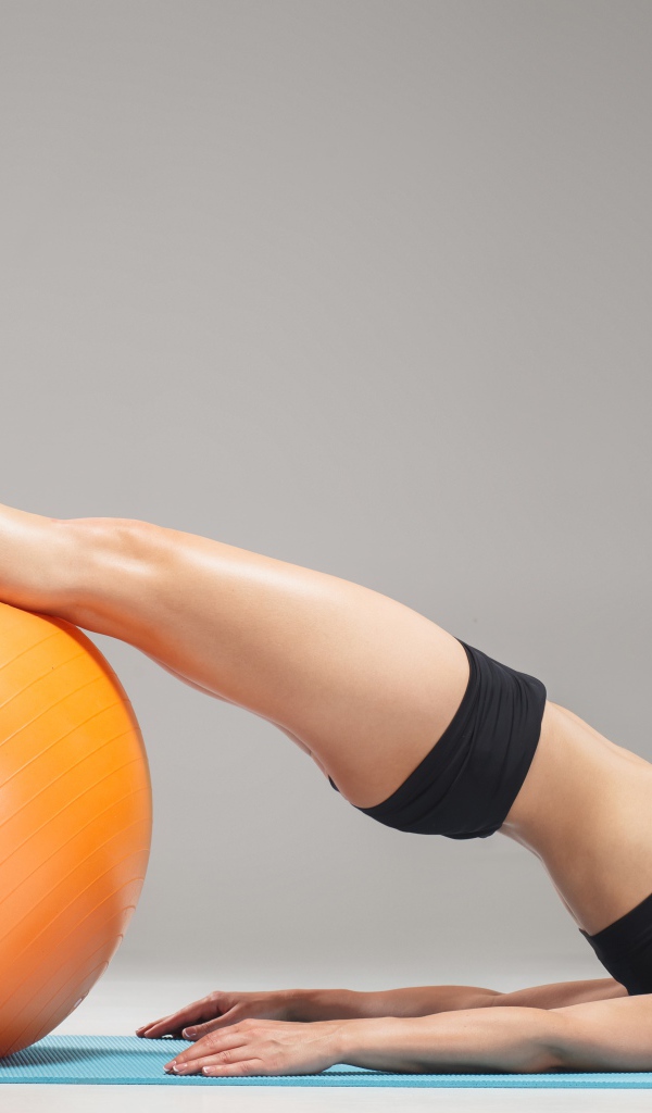 Стройная спортивная девушка занимается на фитболе 