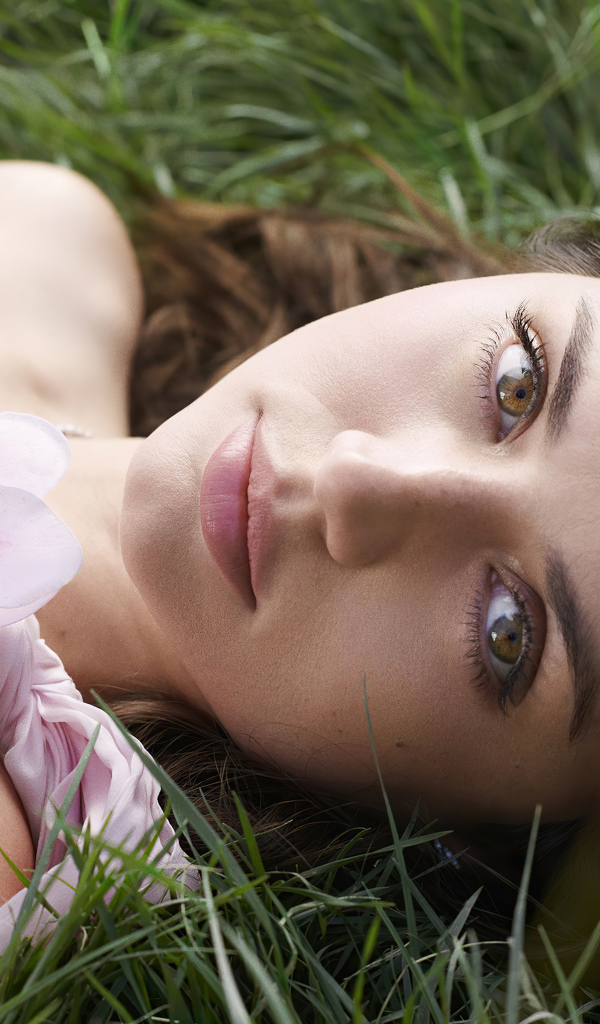 Актриса Ана де Армас лежит на зеленой траве с цветком