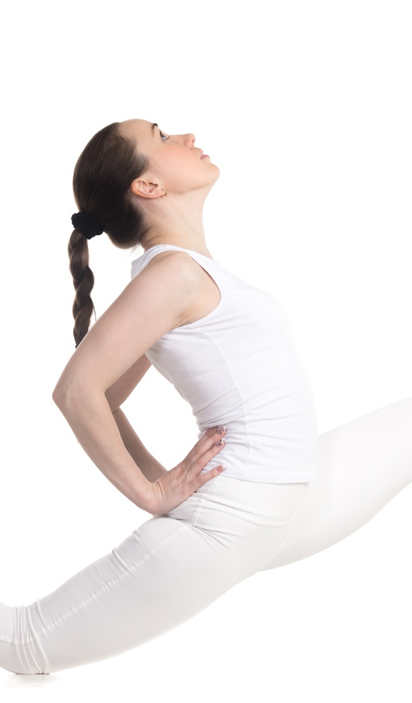 Девушка в белом костюме делает растяжку