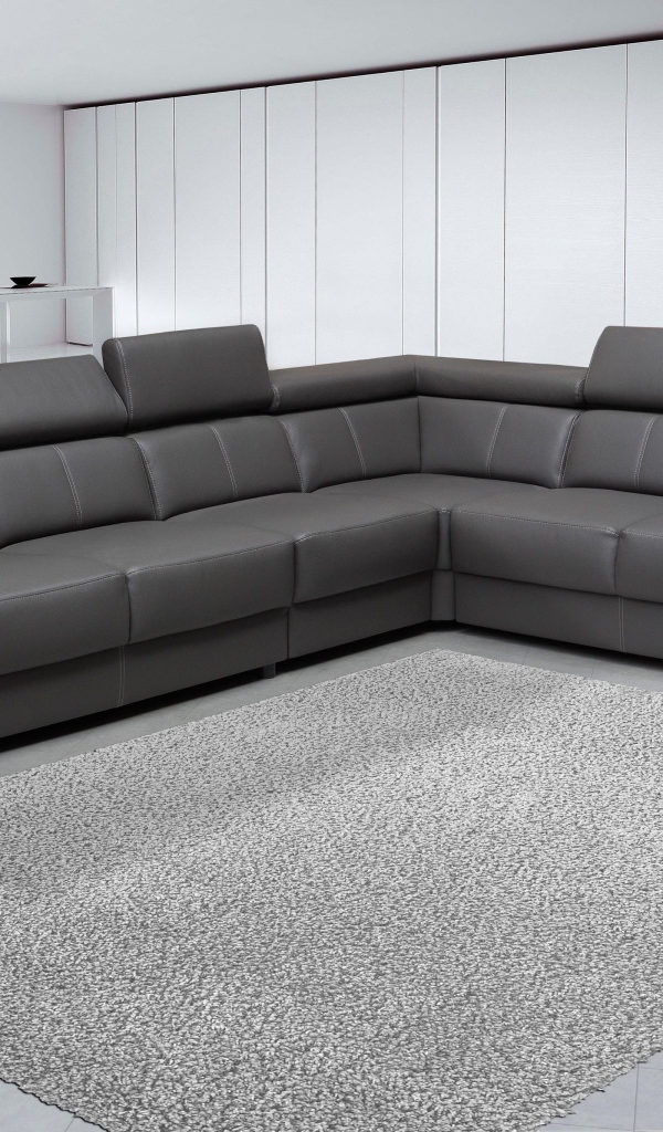 Большой черный угловой диван в комнате с белыми стенами