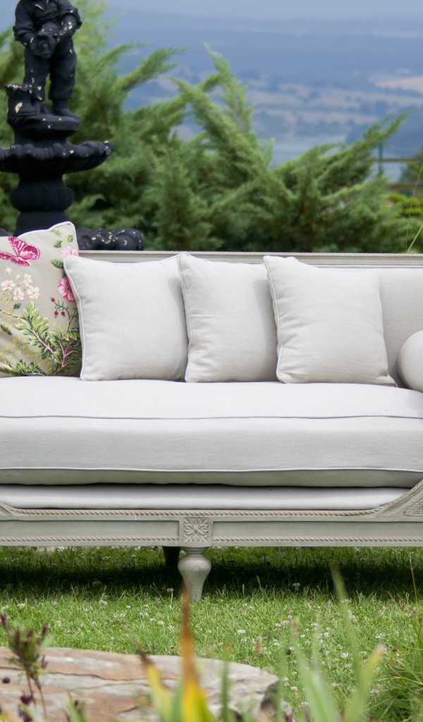 Большой серый диван в саду у пруда 