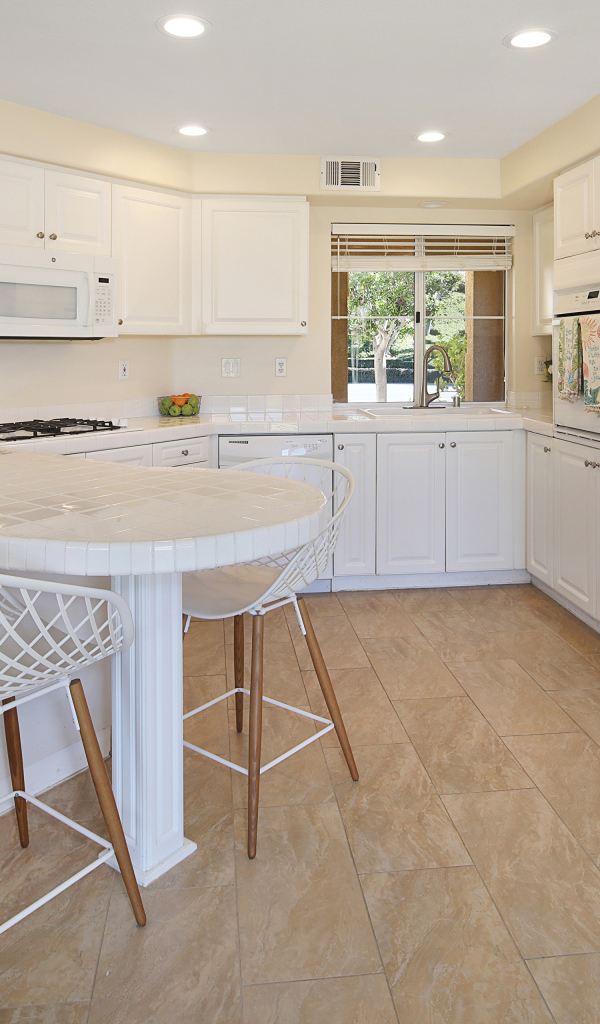 Большой холодильник и белая мебель на кухне 