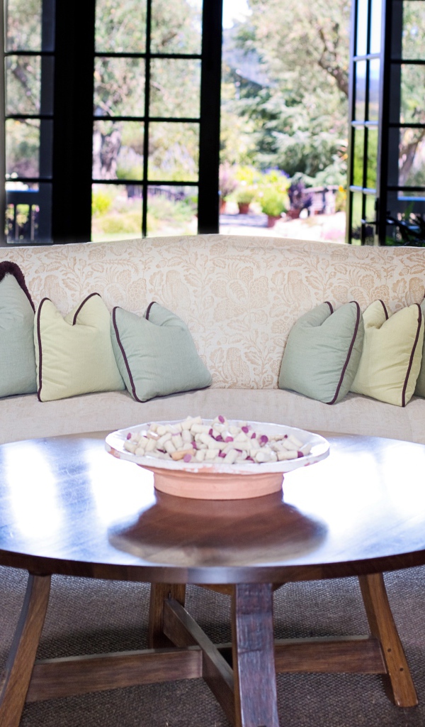 Большой диван с подушками в комнате с круглым столом 