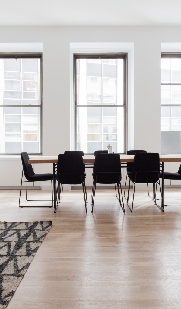 Большой стол с черными стульями в гостиной у окна 