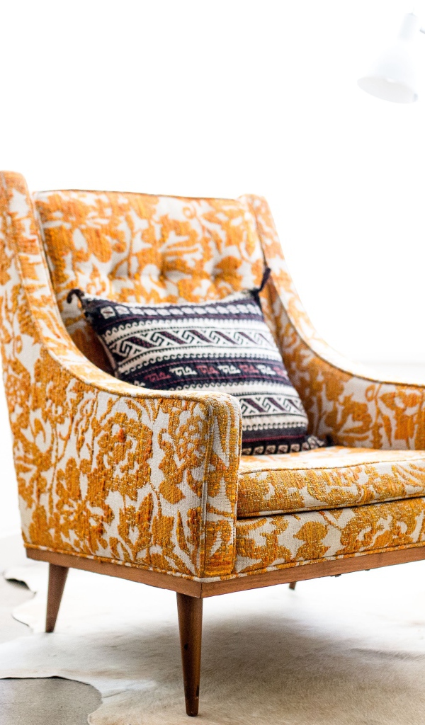 Старое кресло с подушкой в комнате 