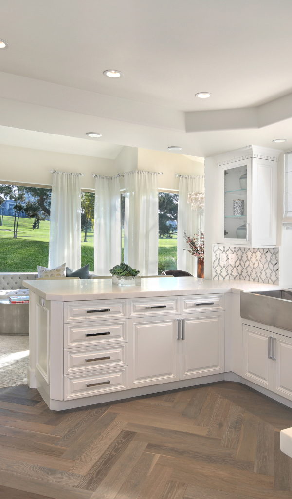 Белый кухонный гарнитур в комнате с большим окном