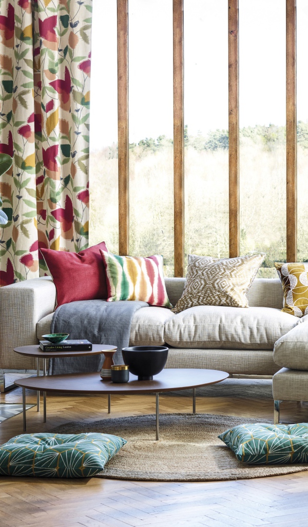 Белый диван с подушками стоит у окна