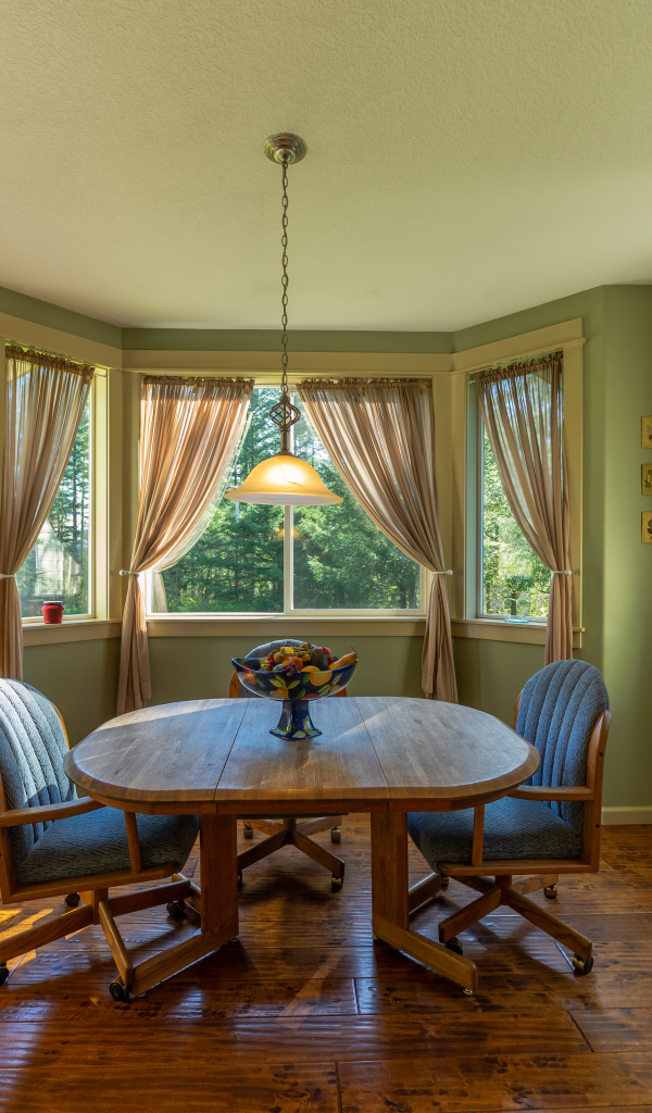 Деревянный стол стоит в гостиной с зелеными стенами