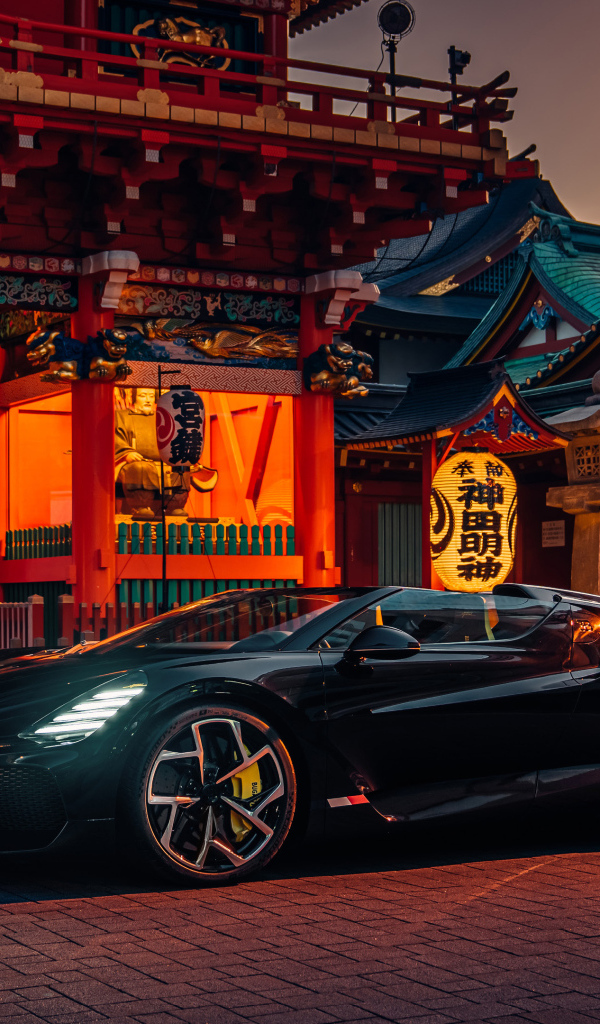 Черный спортивный автомобиль Bugatti W16 Mistral  у здания