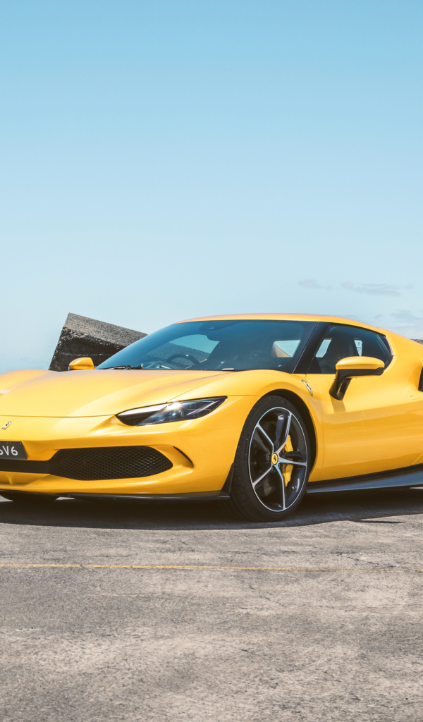 Желтый автомобиль Ferrari 296 GTB у камней