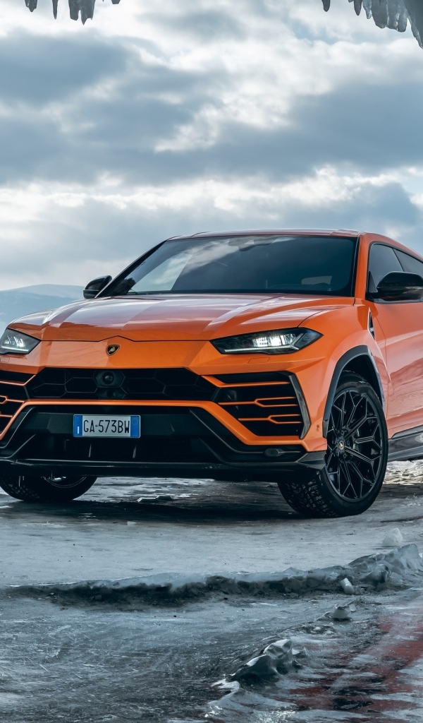 Оранжевый внедорожник Lamborghini Urus у ледяной пещеры
