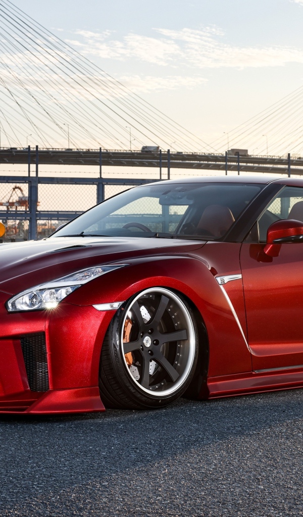 Красный автомобиль Nissan GTR 35R на фоне моста