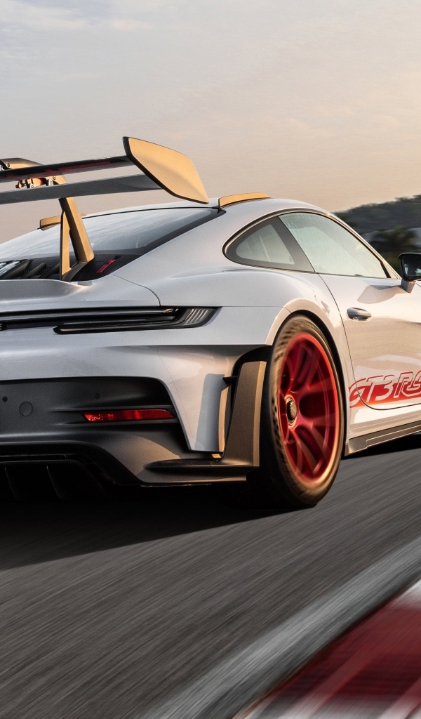 Серебристый спортивный автомобиль Porsche 911 GT3 RS Weissach Package 2023 года на трассе