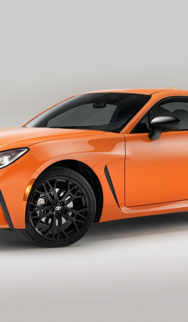 Оранжевый автомобиль Toyota GR 86 на сером фоне