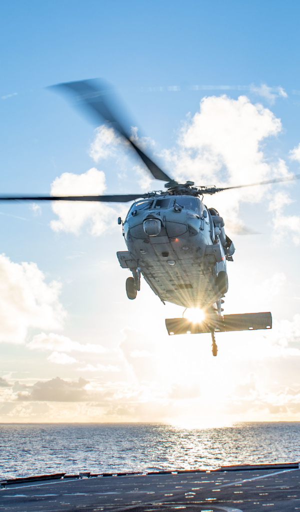 Военный вертолет приземляется на корабль в море