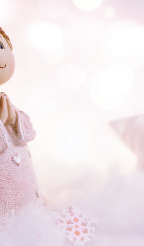 Маленькая статуэтка ангела стоит на снегу