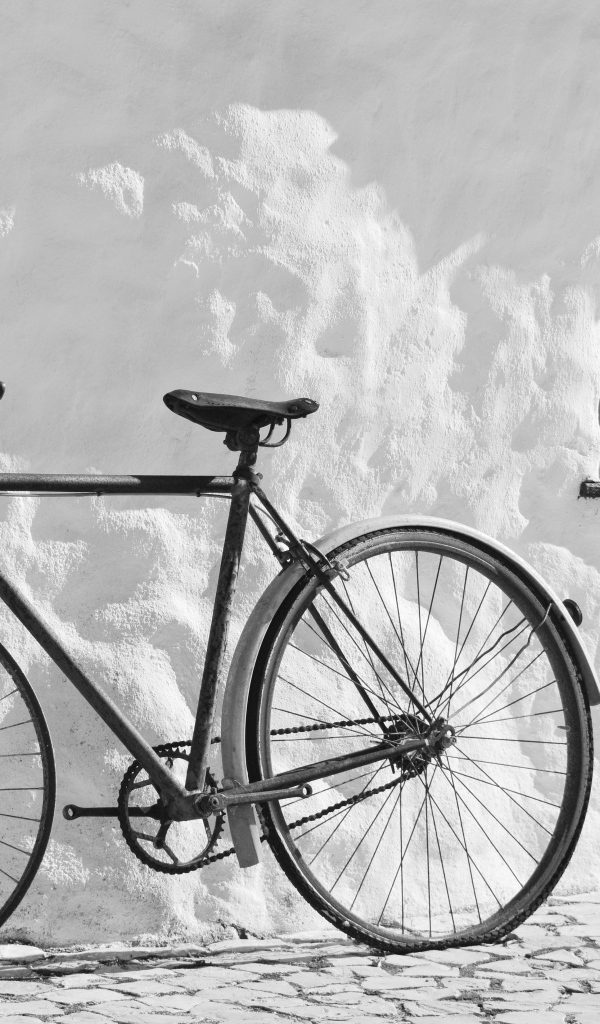 Черный велосипед стоит у белой стены