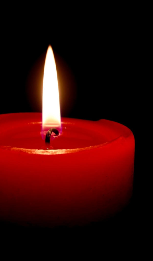 Зажженная красная свеча на черном фоне