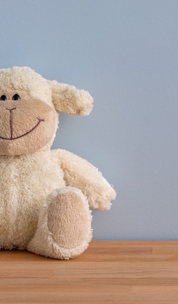 Детская игрушка на полу у серой стены