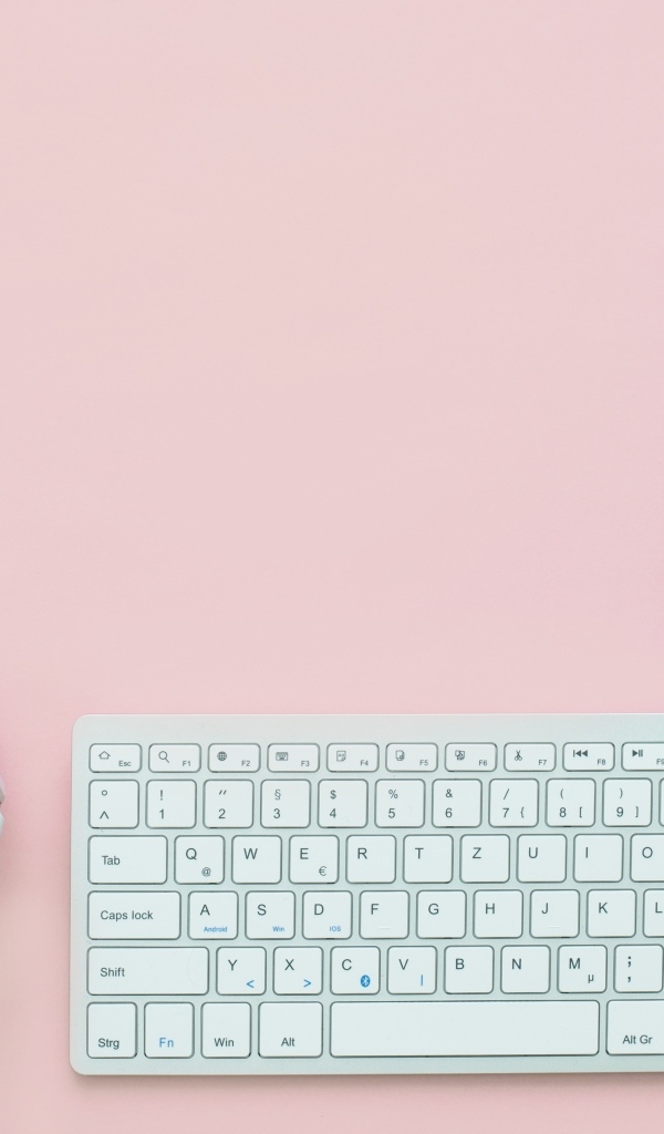 Наушники, клавиатура, блокнот с ручкой и мышка на розовом фоне