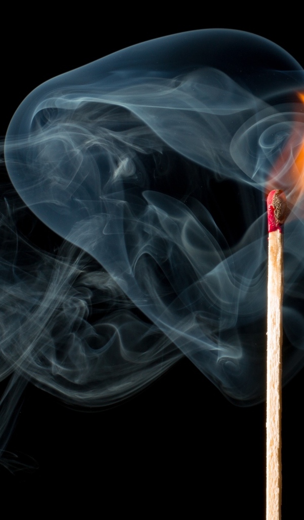 Зажженная спичка с дымом на черном фоне