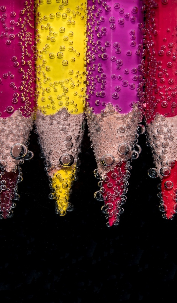 Разноцветные карандаши в пузырях воды на черном фоне