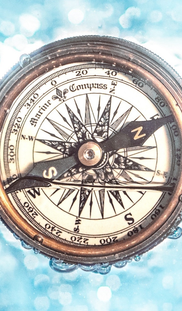 Старый компас в воде на голубом фоне