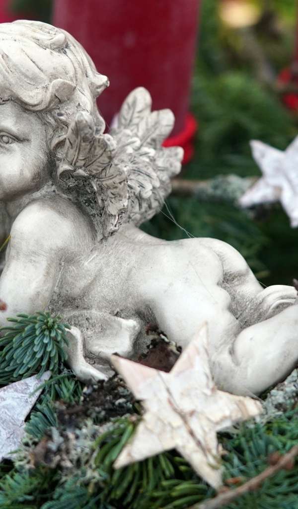 Статуэтка ангел лежит на ветках туи