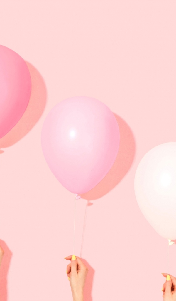 Три воздушных шарика на розовом фоне в руках
